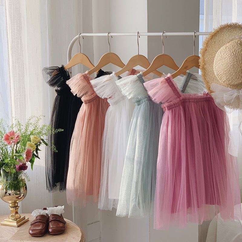 Hangers with colorful tulle skirts and a straw hat on a white background