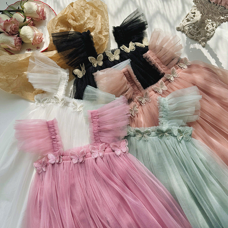 Three children's dresses in pink, black, and green with floral details on a white surface.
